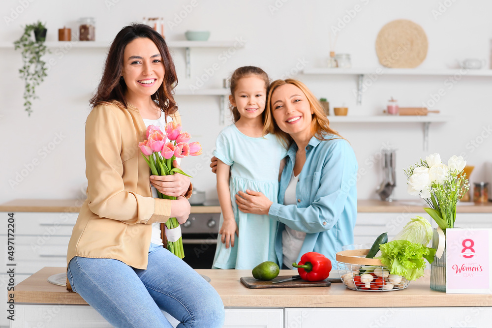 Happy young woman, her little daughter and mother in kitchen at home. International Women's Day celebration