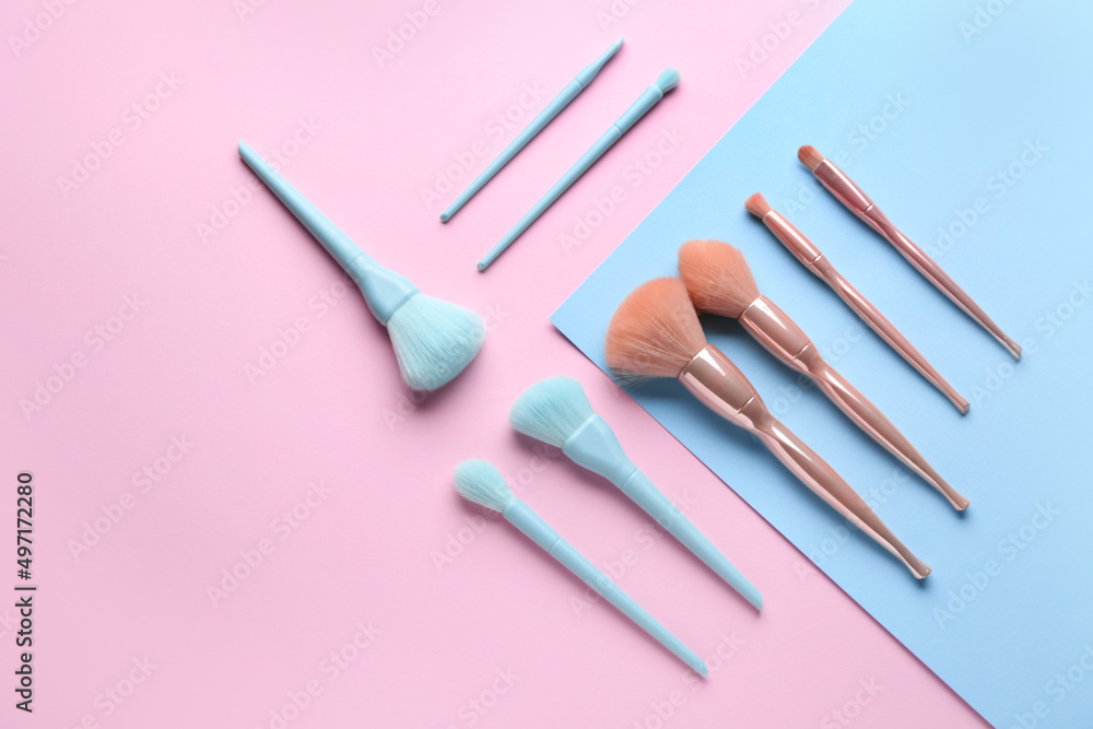 Set of makeup brushes on blue and pink background, top view Set of makeup brushes on blue and pink background, top view