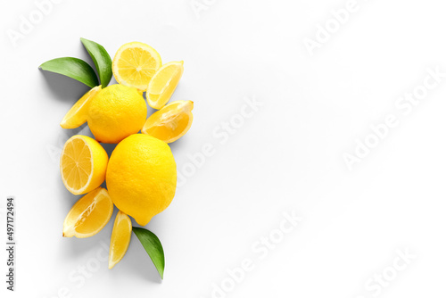 Ripe lemons and slices on white background, top view