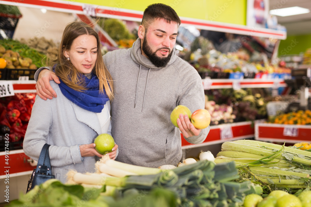 Fototapeta premium Friendly couple examining apples in grocery shop. High quality photo