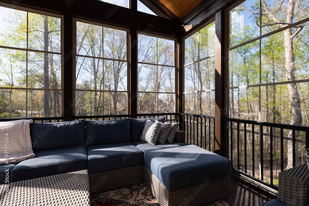 Contemporary screened porch in springtime, full of blooms trees in the background.
