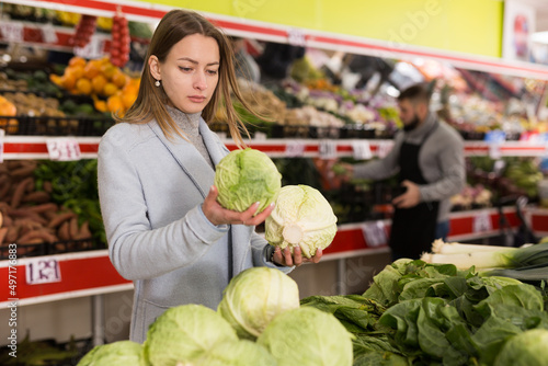 Portrait of adult woman buying fresh cabbage in grocery shop. High quality photo
