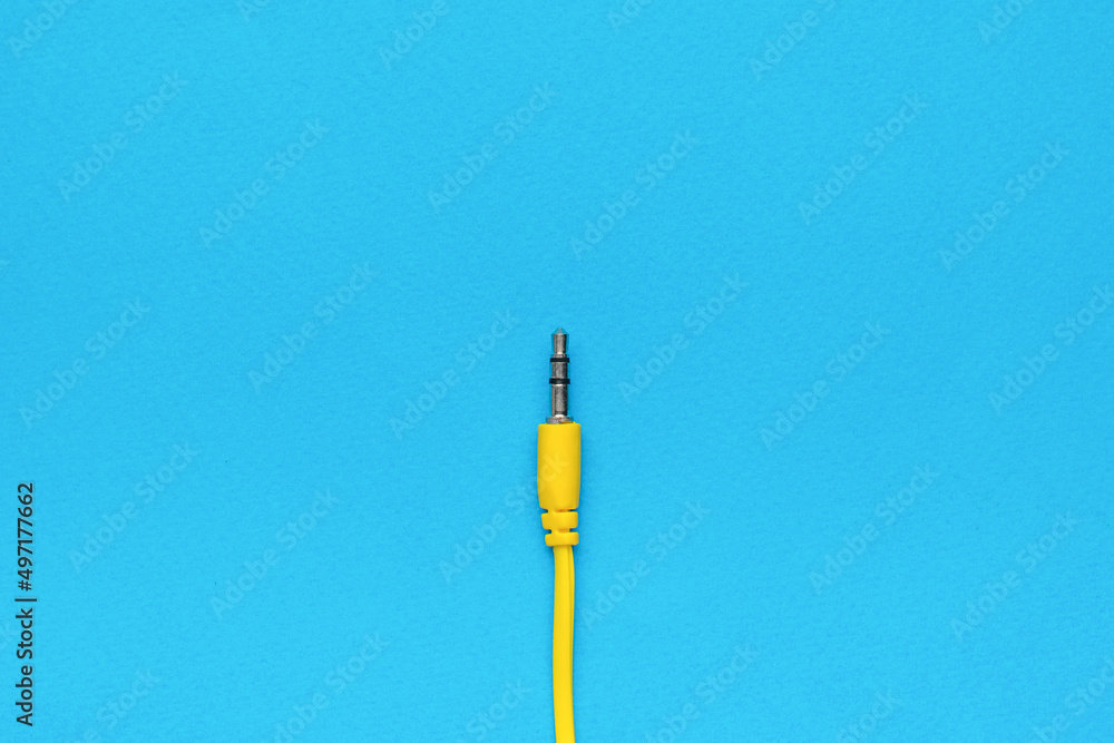 The central composition of the yellow audio jack on a blue background. Flat lay. The central composition of the yellow audio jack on a blue background. Flat lay.