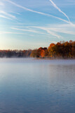 View of Blue Skies Along Foggy Lake with Trees with Fall Foliage 