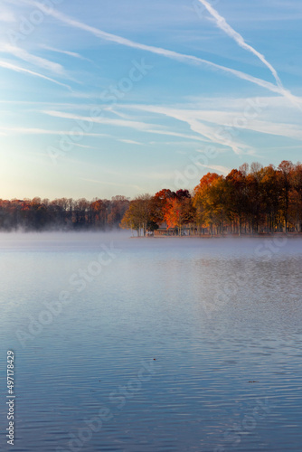 View of Blue Skies Along Foggy Lake with Trees with Fall Foliage 