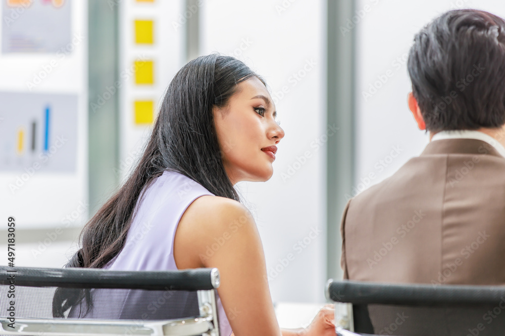 Asian young pretty professional businesswoman employee staff in sleeveless shirt sitting talking discussing with male colleague businessman in formal business suit at working desk in company office Asian young pretty professional businesswoman employee staff in sleeveless shirt sitting talking discussing with male colleague businessman in formal business suit at working desk in company office