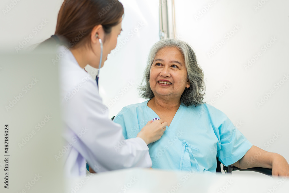 Physician examining heart with a stethoscope and talking with a senior woman at a clinic for check yearly checkup, Medicine health care service and medical insurance concept. Physician examining heart with a stethoscope and talking with a senior woman at a clinic for check yearly checkup, Medicine health care service and medical insurance concept.