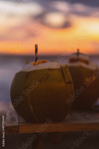 Coconuts with a straw on sunset background, tropical life