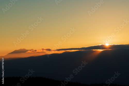 高ボッチ高原から見る日没間近でシルエットになった御嶽山と光芒さす山々