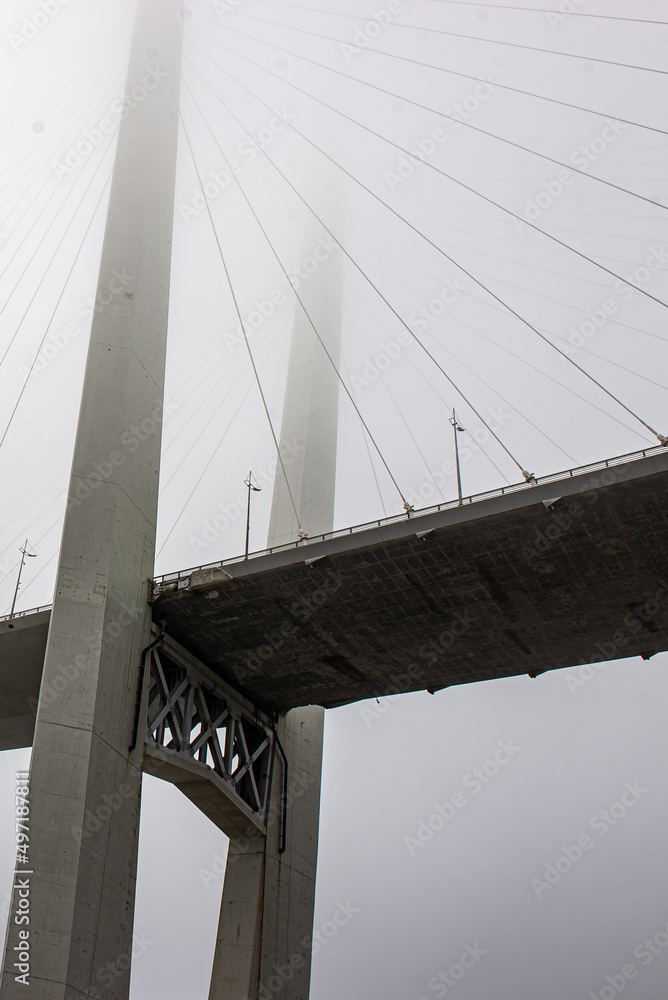 Fototapeta premium a beautiful bridge over the sea disappears in the fog. the bridge dissolves into the sky.