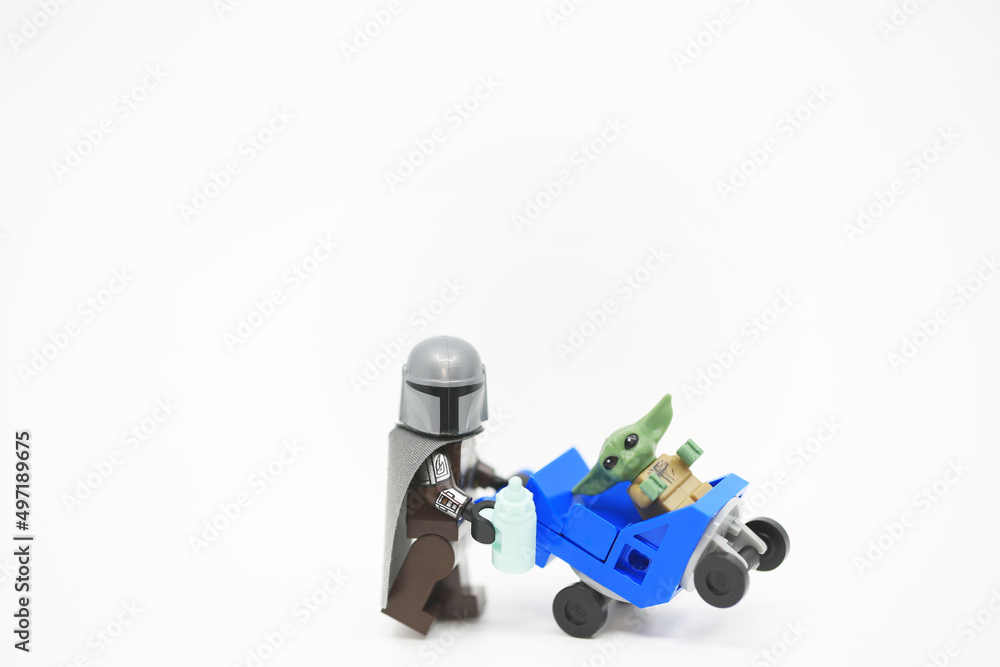 Naklejka premium Hong Kong - April 4 2022: The Mandalorian take care his baby yoda in the form of minifigure toy