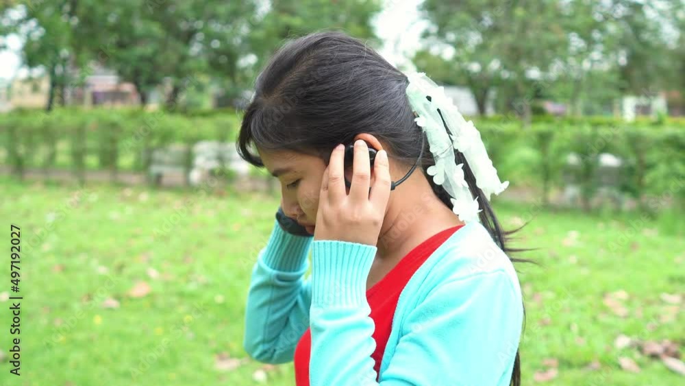 Asian woman wearing red shirt wearing bluetooth headphones on wrist with smart watch ready for exercise in park Asian woman wearing red shirt wearing bluetooth headphones on wrist with smart watch ready for exercise in park