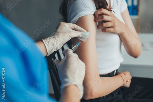 Doctor wearing white gloves giving COVID -19 coronavirus vaccine injection to a woman's arm in clinic. Coronavirus prevention. Woman getting vaccination