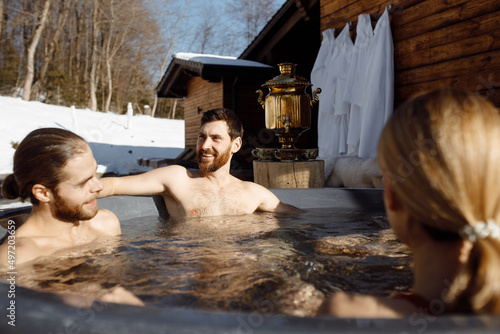 Young and happy caucasian man with friends relaxing and enjoying vacation in jacuzzi, side view