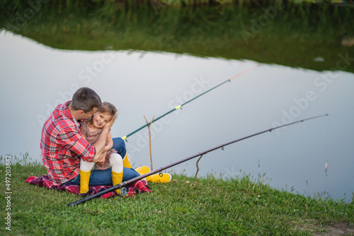 Dad and little daughter have fun outdoors, fishing on the lake
