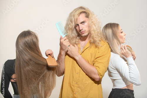 Group of young women and man combing hair. People combing hair, girls and guy use hair comb, takes care procedures.