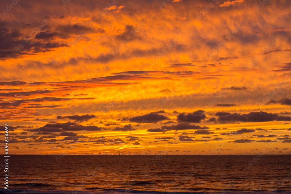 Yellow and orange sundown. The sundown over the ocean without sun. Orange and yellow cloudy evening sky