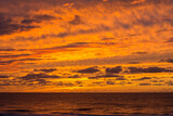 Yellow and orange sundown. The sundown over the ocean without sun. Orange and yellow cloudy evening sky