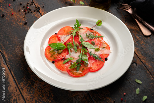 Light Salad with thinly sliced tomatoes, arugula, parmesan, capers and balsamic sauce. Vegetarian tomato salad