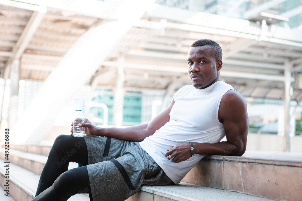 Fototapeta premium Runner drinking water while resting after workout.