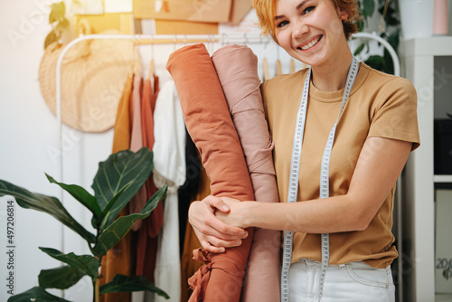 Happy smiling seamstress hugging rolls of fabric photo