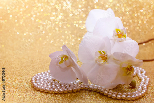 Fototapeta Naklejka Na Ścianę i Meble -  white Orchid and pearl necklace on a shiny gold background
