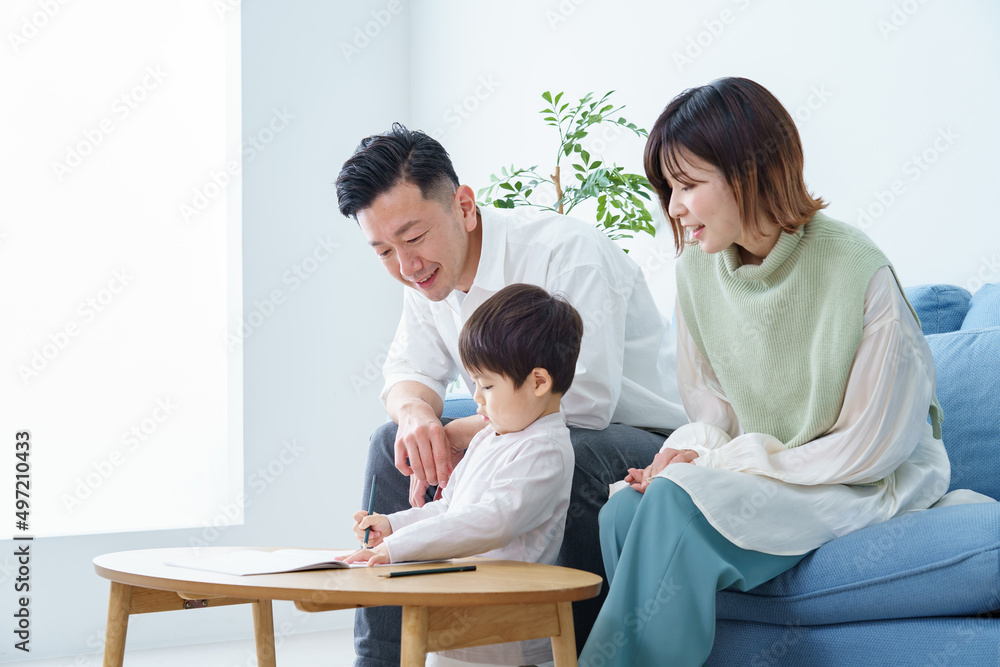A boy working on drawing with a pencil and his parents watching over it A boy working on drawing with a pencil and his parents watching over it