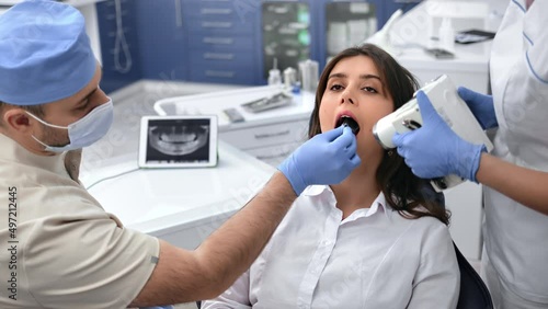 Professional stomatologist male doctor and female assistant roentgen shooting mouth cavity patient  photo