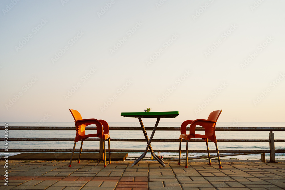 Orange plastic chairs with furniture at the seaside terrace with sky on background