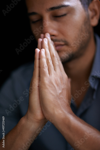 Praying for guidance and strength. Cropped shot of a young man holding his hands together in prayer.