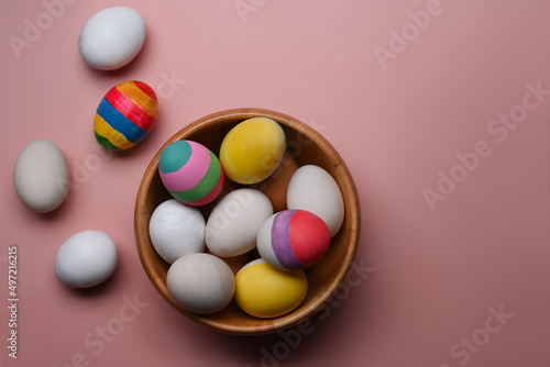 Easter basket filled with painted  Easter Eggs over pink background.