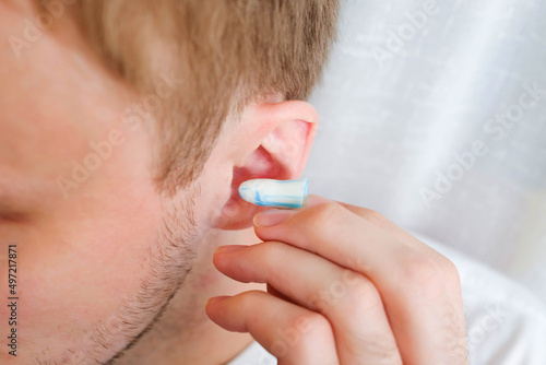 White and blue ear plug puts in the ear photo