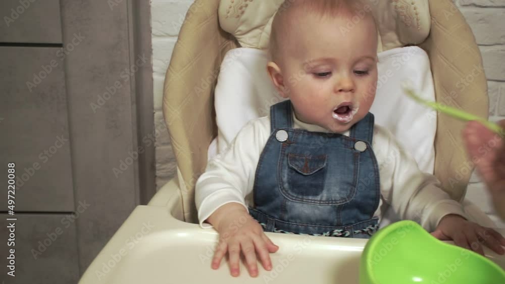 dad's hand feeds baby yogurt from spoon dad's hand feeds baby yogurt from spoon