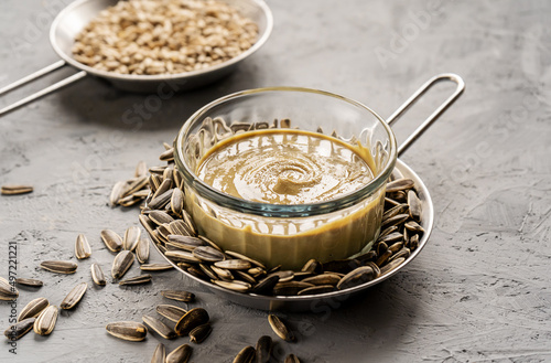 Homemade sunflower seeds' butter or spread with roasted seeds on grey background