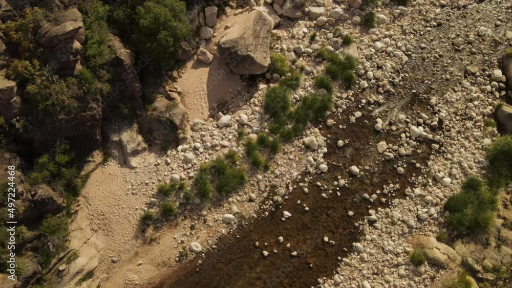 Aerial top down shot of person walking by river rocks during sunny day in Argentinian Landscape Aerial top down shot of person walking by river rocks during sunny day in Argentinian Landscape