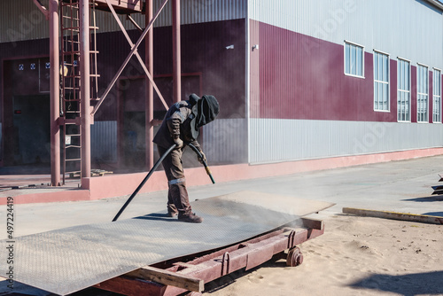 Bilde på lerret A worker in a special suit is sandblasting metal at an industrial site