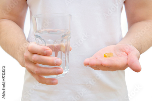 Man holding fish oil pill and glass of water