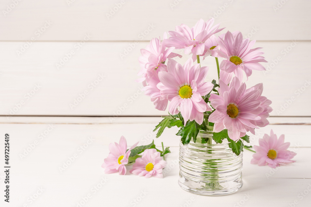 Blooming chrysanthemums in a glass on a light wooden background. Blooming chrysanthemums in a glass on a light wooden background.