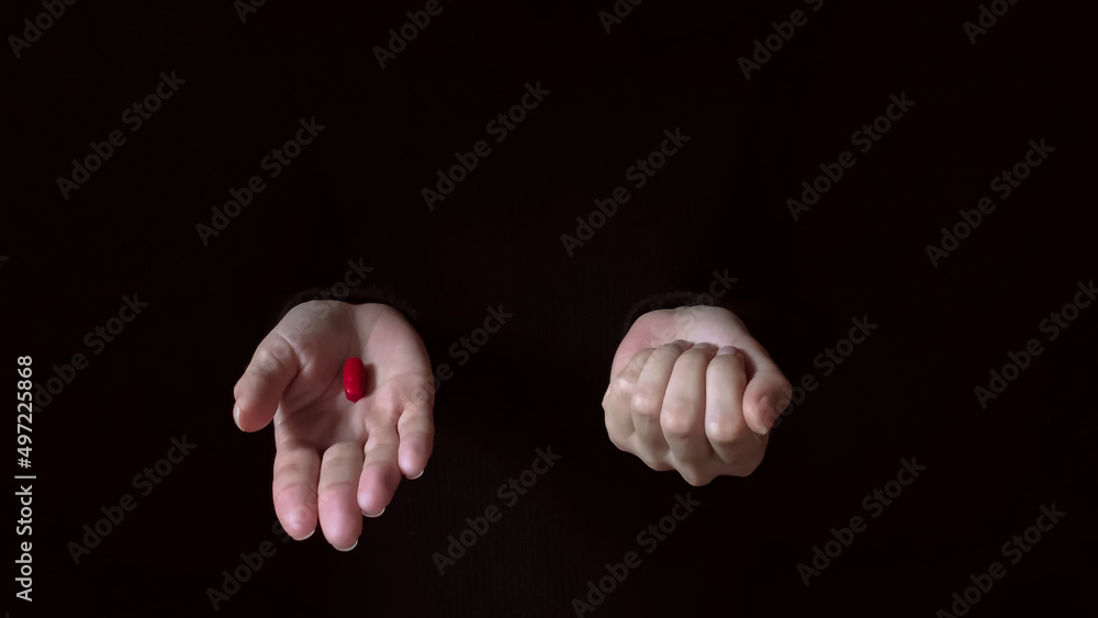 Red and blue pills on hands isolated on a black background. Hand offering a red pill