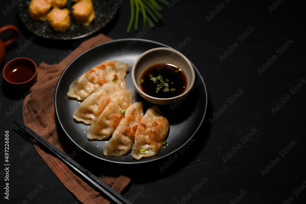 Fototapeta premium Flavorful Asian Chinese fried dumplings or gyoza on black table.