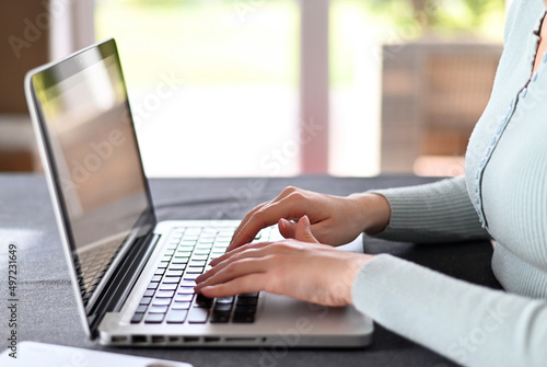 Businesswoman's hands presses on a laptop keyboard, Using computers. Remote working from home. Freelancer workplace in kitchen with laptop