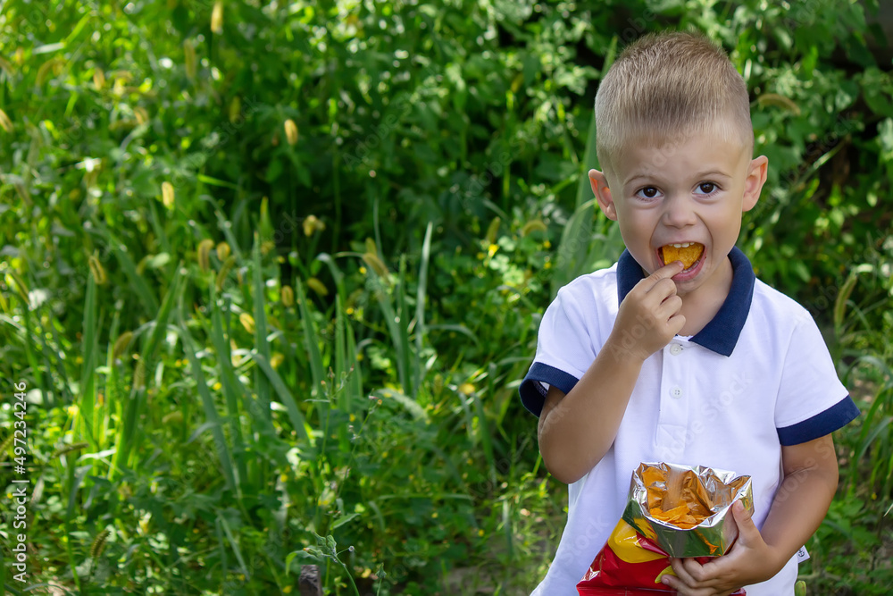 potato chips in the boy's hand, the boy eats the chips. potato chips in the boy's hand, the boy eats the chips.