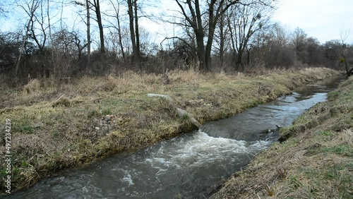 The small river Uherka flows quickly in eastern Poland, cloudy day photo