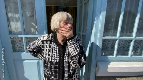An elderly woman stands on the porch of a rural house in Ternopil region, Ukraine