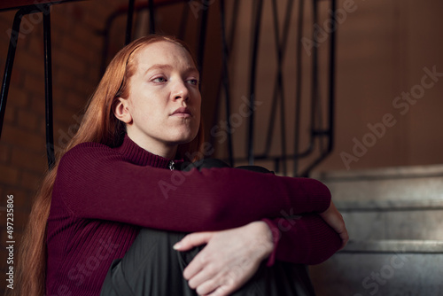 Young redhead woman sitting on stairs