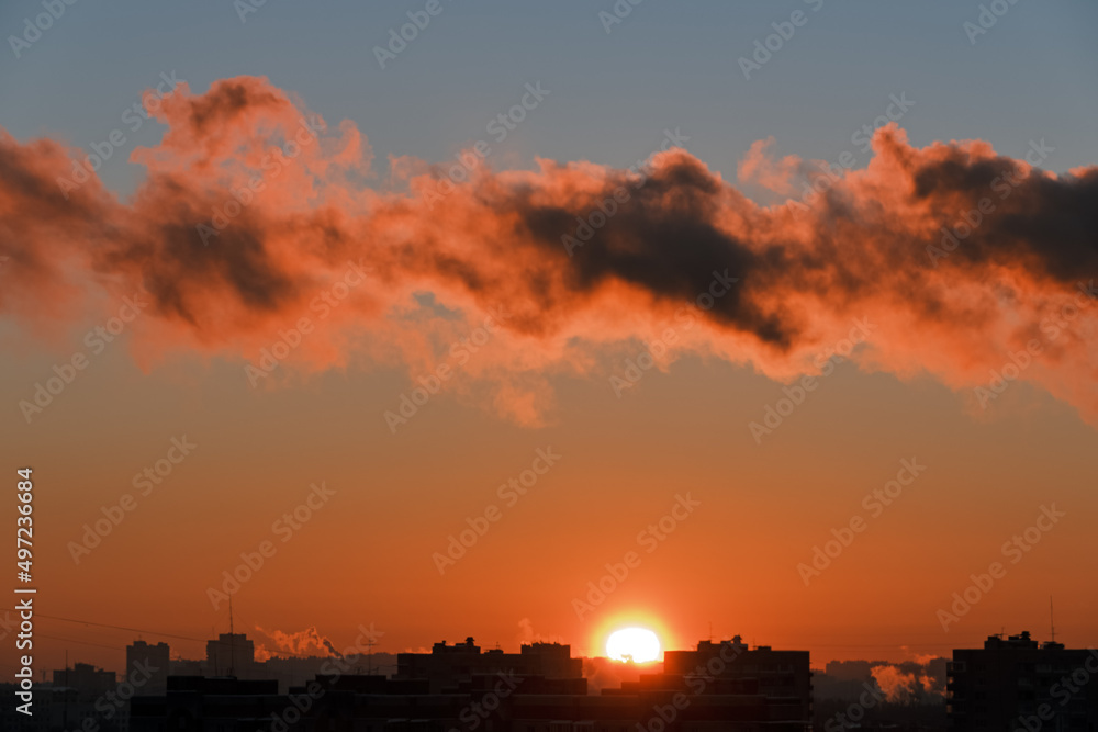 Cityscape at sunset . The sun sets over the horizon over the rooftops. Photo of the city in the golden hour.