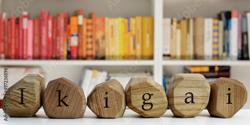 Ikigai word (Japanese word for reason for being) written on wooden blocks. Blurred books behind. Life meaning concept. photo