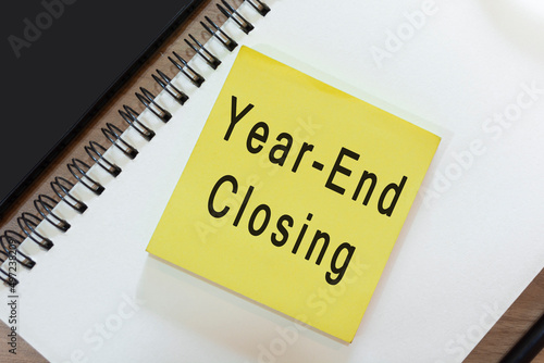 Text on yellow note with notepad on wooden desk - Year-end closing
