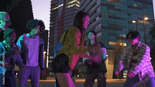Young Asian Chinese Girl having fun dancing with group of Generation Z friends in music street party in the city at night photo