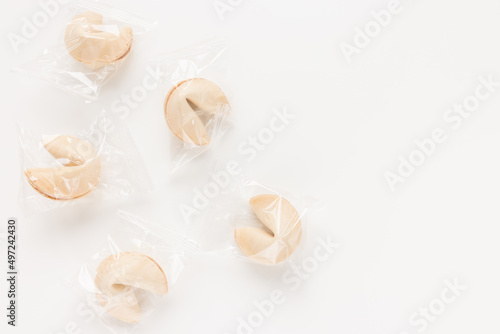 Fresh and tasty Chinese fortune cookies, individually wrapped in foil on white background. Top view, copy space